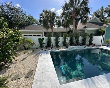 a pool with pavers and a house in the background