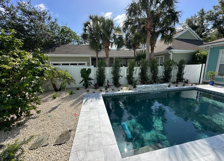 a pool with pavers and a house in the background